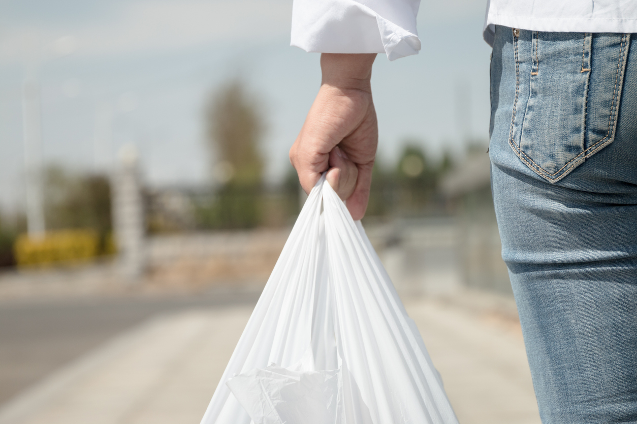 Une femme tient un sac en plastique d'une épicerie