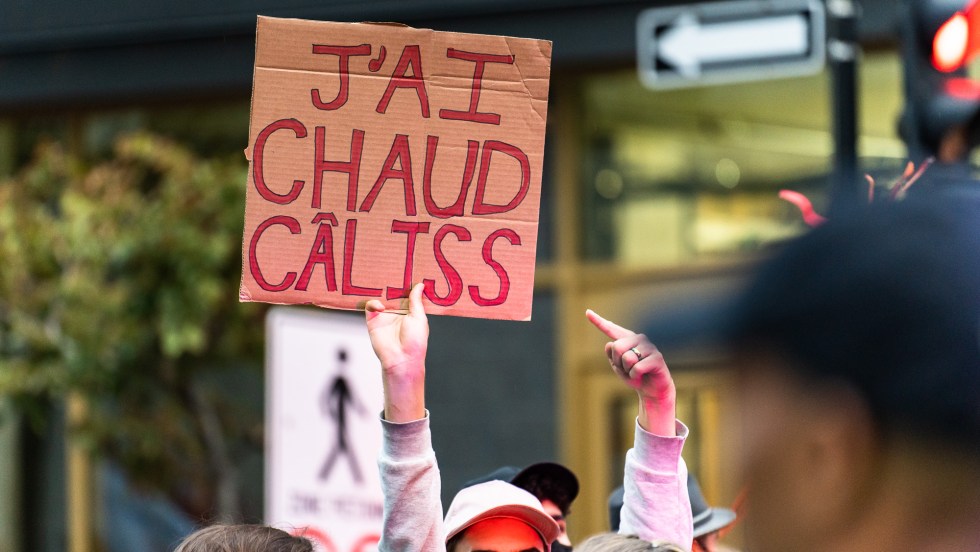 Un manifestant écologiste tient une pancarte qui dit «J'ai chaud câliss» pendant une manifestation pour l'environnement avant le débat des chefs à TVA.
