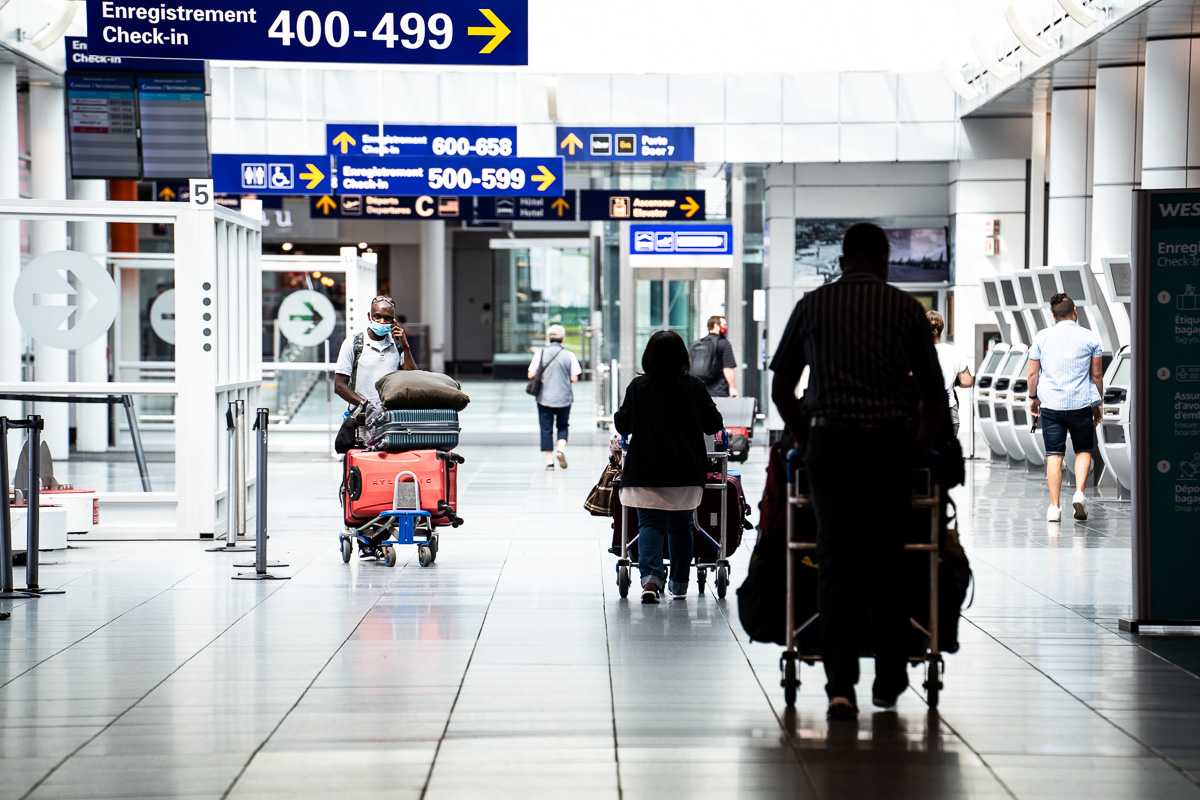 Des voyageurs à l'étage des départs à l'aéroport de Montréal.