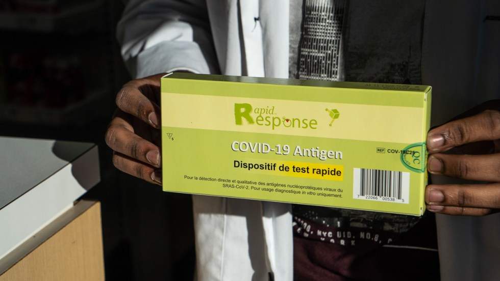 Un employé de pharmacie tient un dispositif de test rapide pour la COVID-19.
