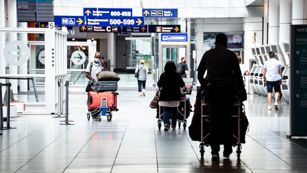 Des voyageurs à l'étage des départs à l'aéroport de Montréal.