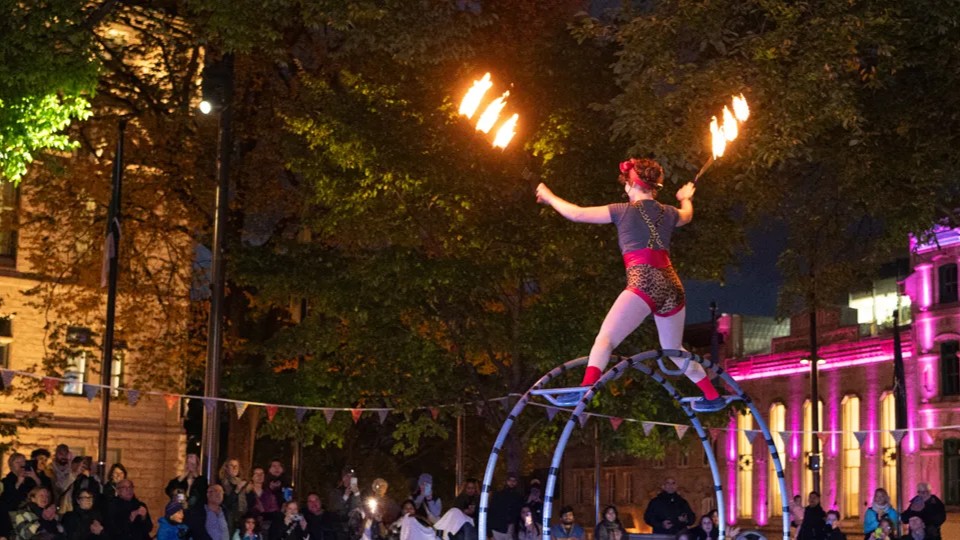 Une artiste du cirque jongle avec du feu en équilibre sur une roue.