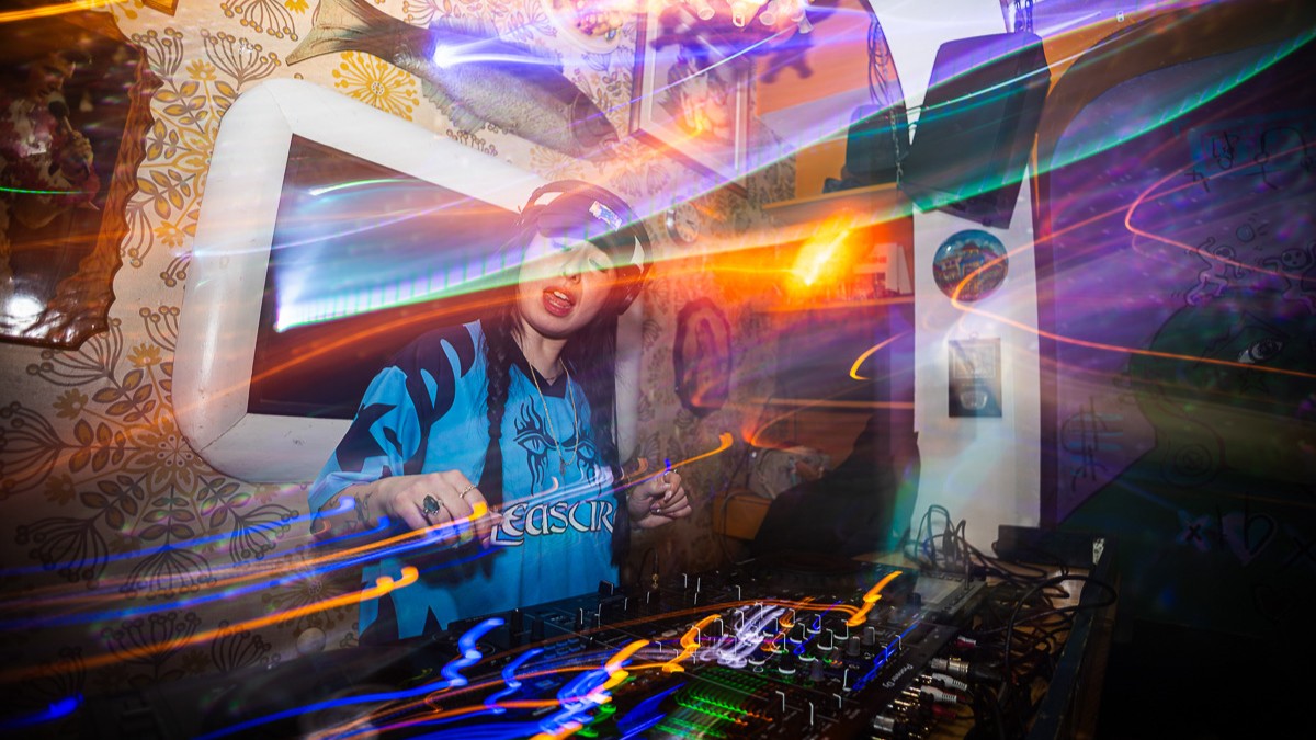 Um DJ joue de la musique derrière sa table.