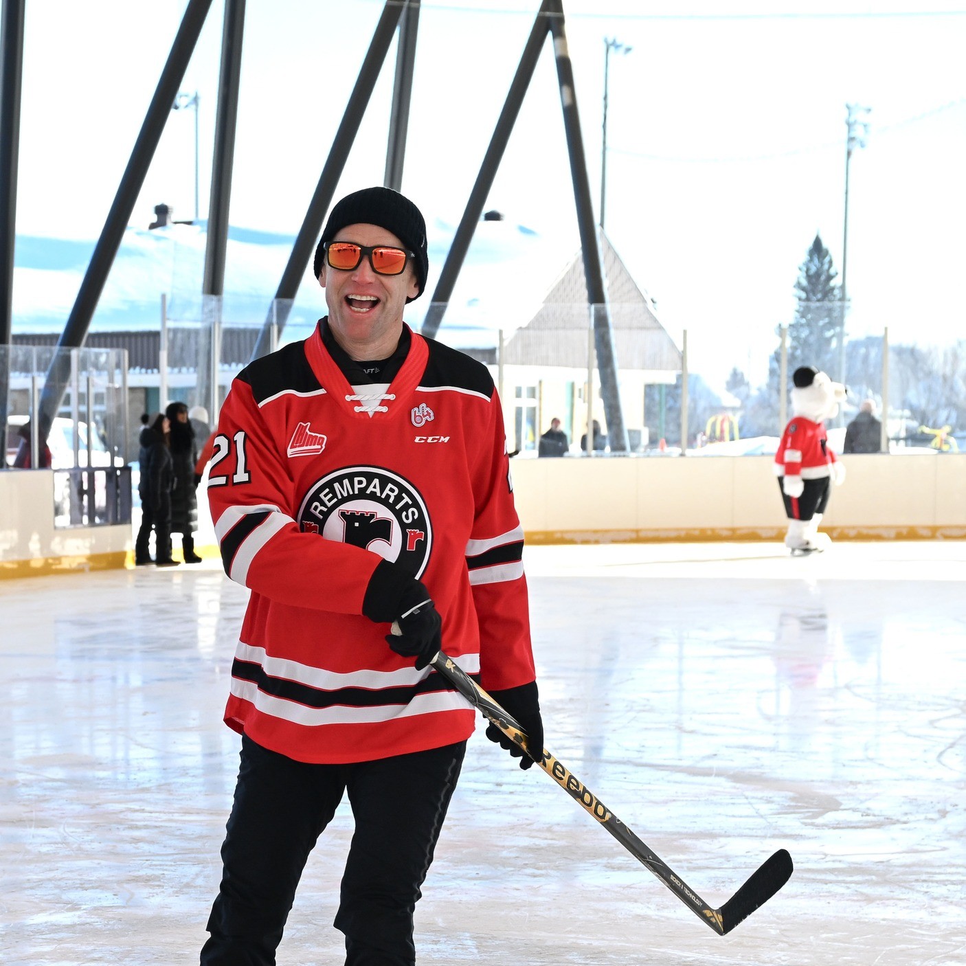 Le maire de Québec, Bruno Marchand, sur une patinoire portant un chandail des Remparts et tenant un bâton de hockey.