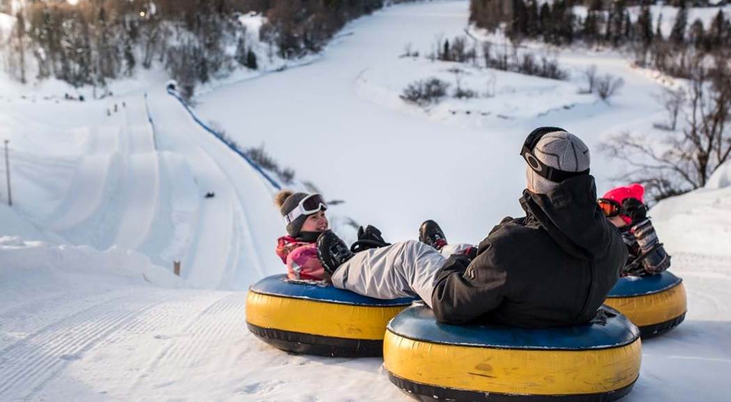 Une famille glisse sur des tubes au Centre de jeux d'hiver Valcartier.
