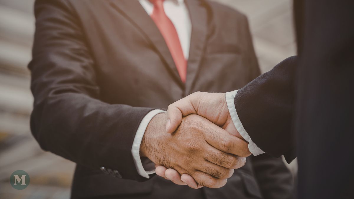 Un homme d'affaires plus âgé serre la main d'un homme d'affaires plus jeune.