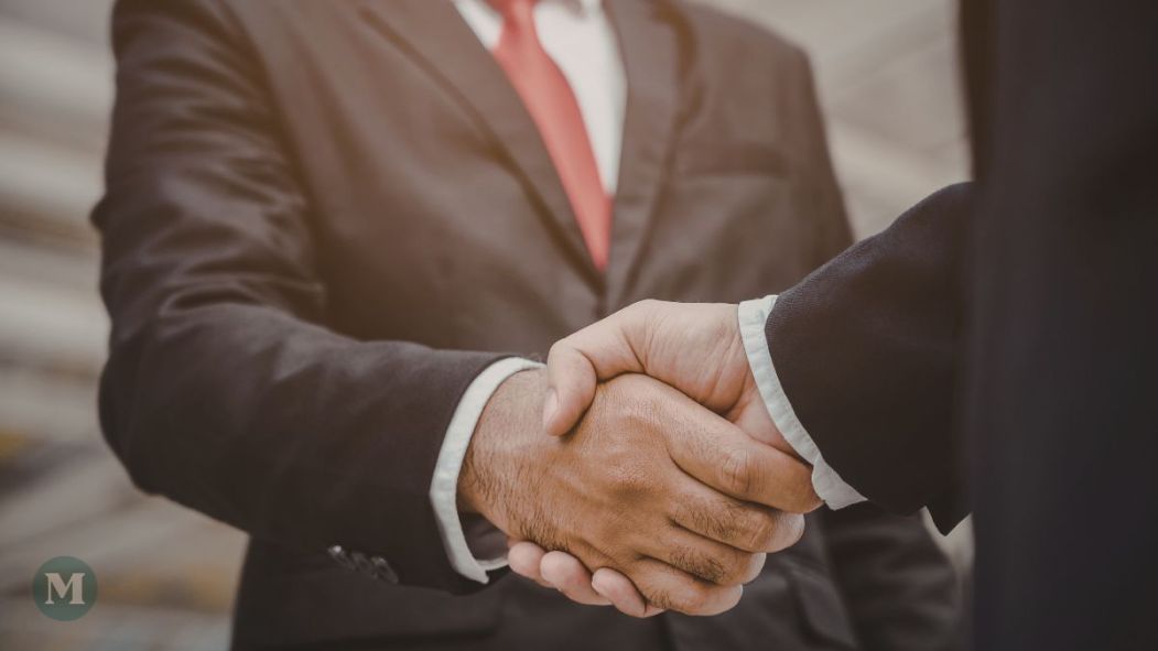 Un homme d'affaires plus âgé serre la main d'un homme d'affaires plus jeune.