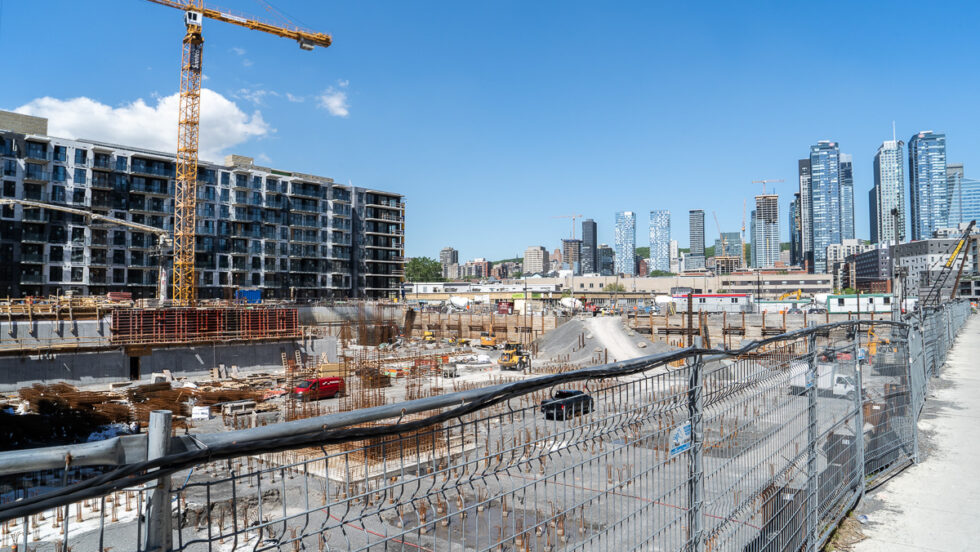 Près d'un chantier de Griffintown, des grues sont visibles autour des grattes-ciel du centre-ville de Montréal.